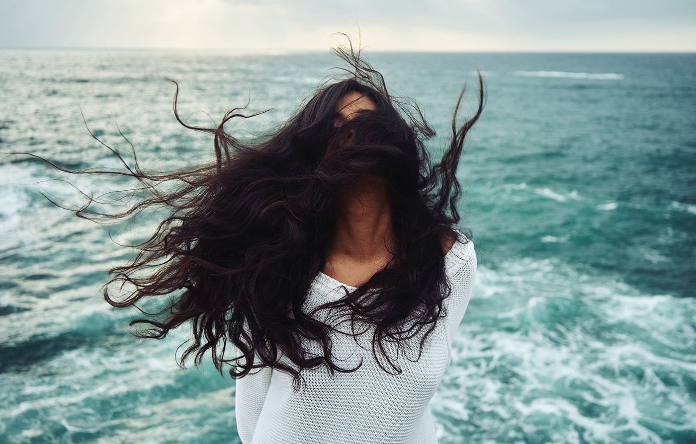 Woman shaking hair in front of ocean