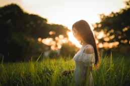 Woman outside in field at sunset