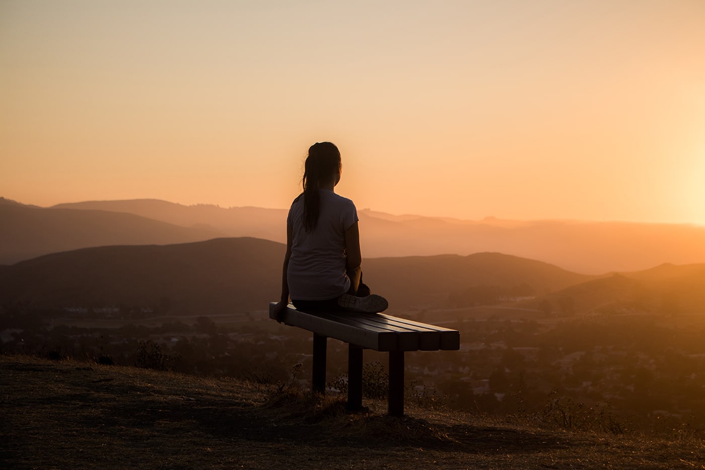 Woman with depression sitting outside at sunset