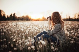 Woman photographer sitting in field
