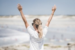 Excited woman with arms up on beach