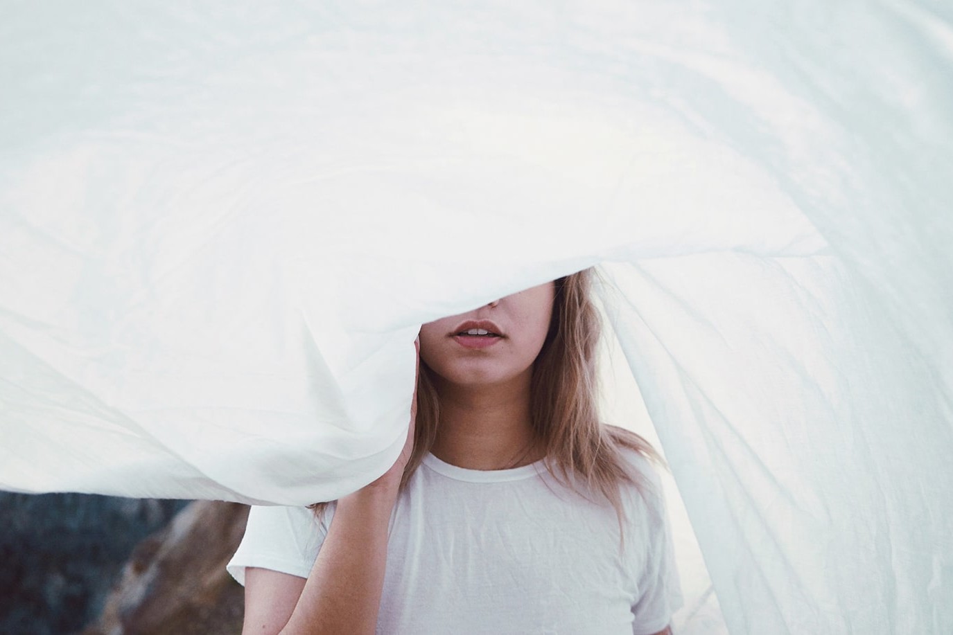 Woman standing behind white sheet covering face
