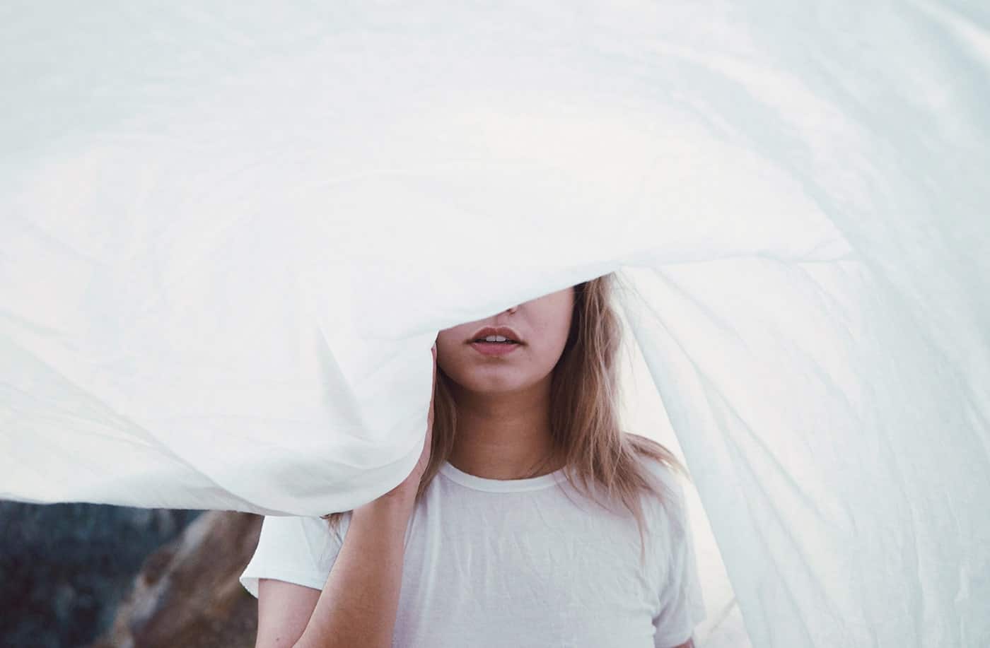 Woman standing behind white sheet covering face
