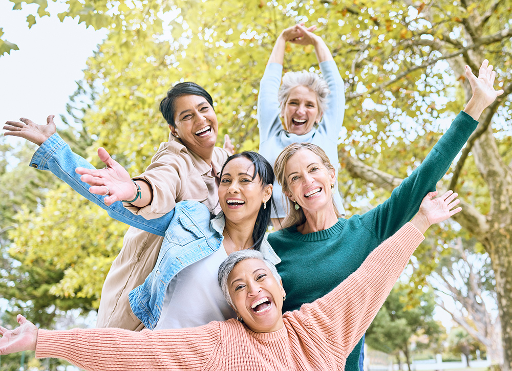 A group of five happy healthy older women outside in a park
